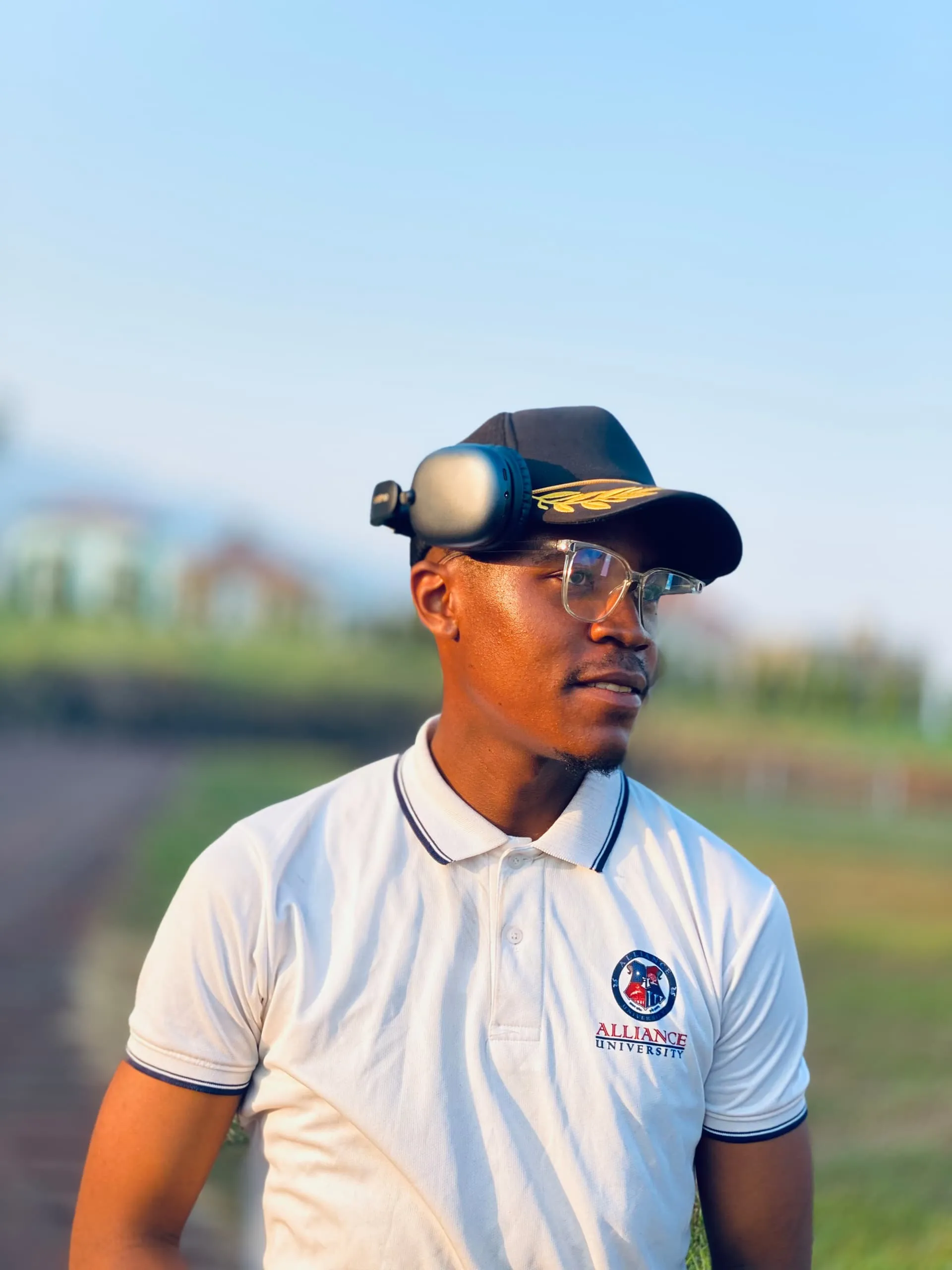 Chifen outdoors in a white polo shirt, cap and headphones, looking off to the side.