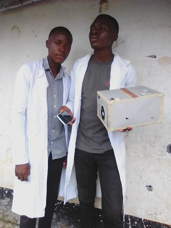 Chifen and a collaborator in lab coats holding the air sanitiser prototype.